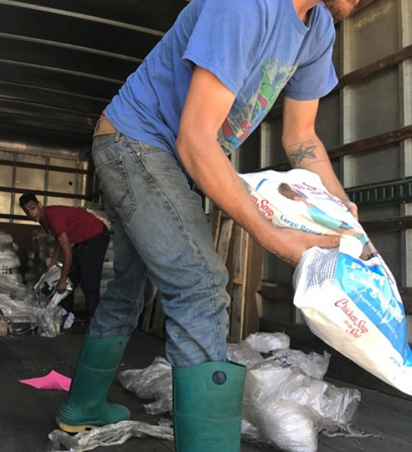 FABFAS Sebastian County AR image: two volunteers carry dog food bags within truck